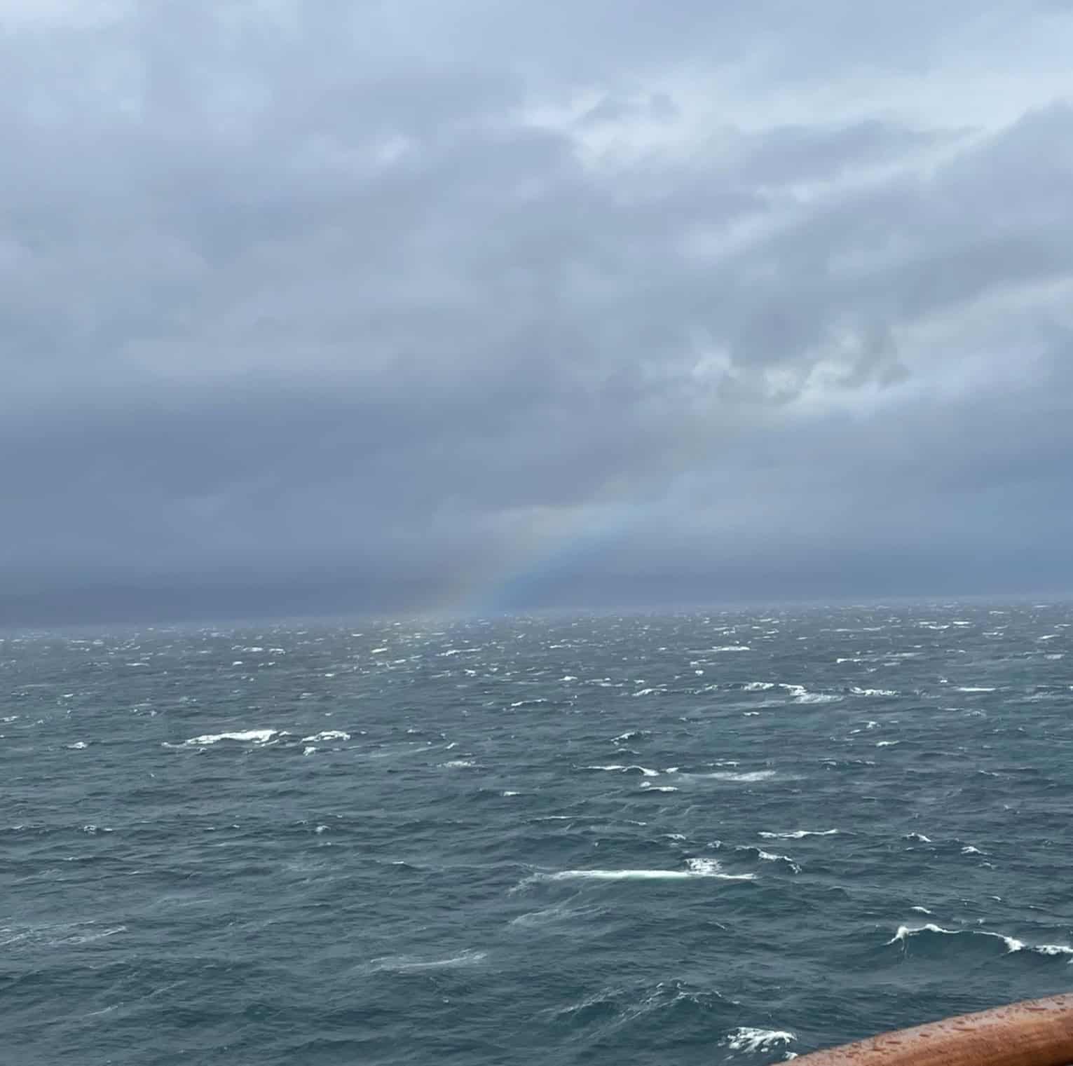 Waves on the ocean with a faint rainbow in the middle of the air